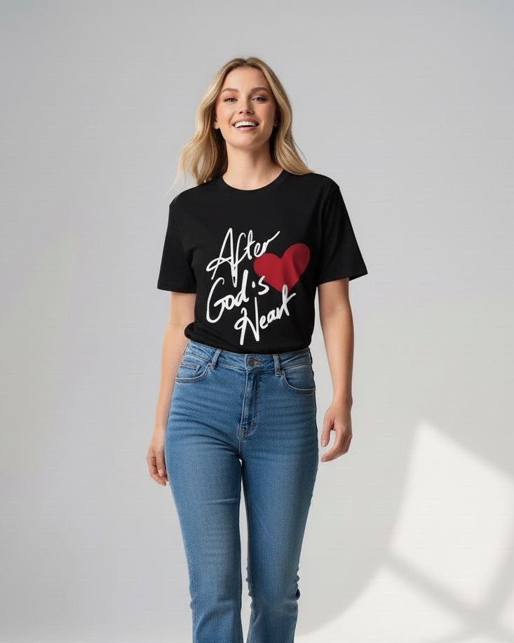 Woman wearing a black t-shirt with text and a red heart design, standing against a white background