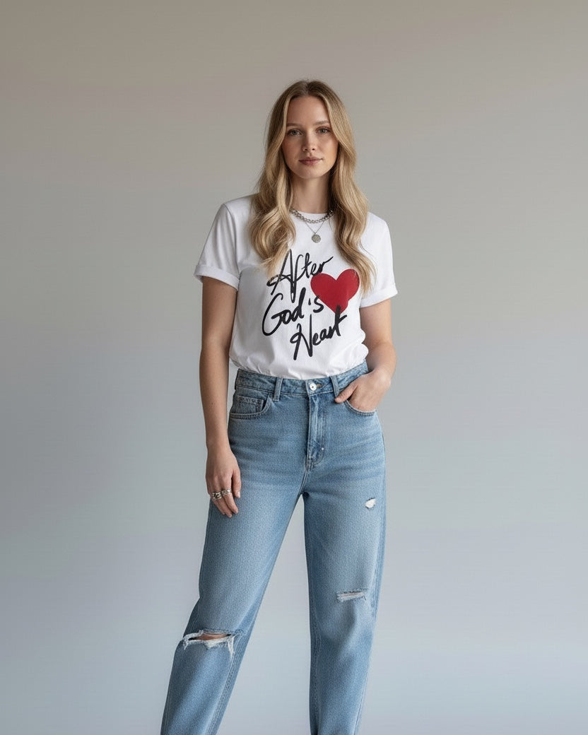 Woman wearing a white t-shirt with text and graphics, light blue jeans, and white sneakers on a plain background