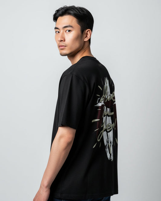 Man wearing a christian black t-shirt with graphic design on the back against a gray background