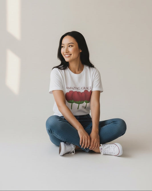 Person wearing a white t-shirt with a graphic design sitting on the floor.
