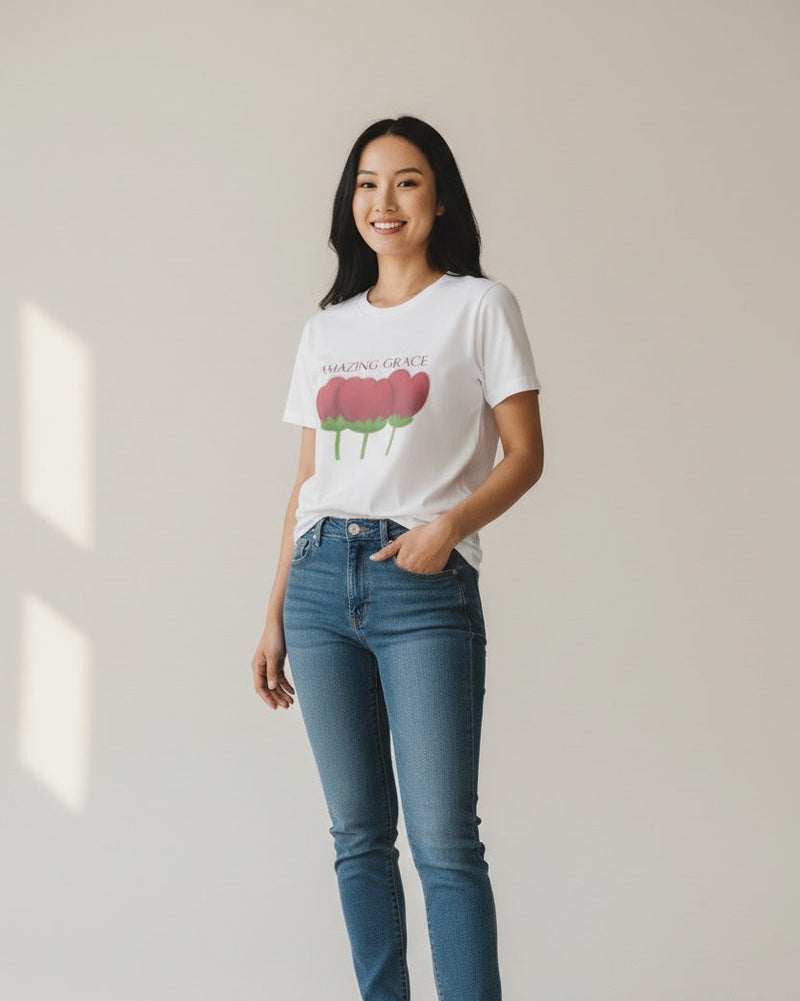 Woman wearing a white t-shirt with a graphic design and blue jeans on a plain background