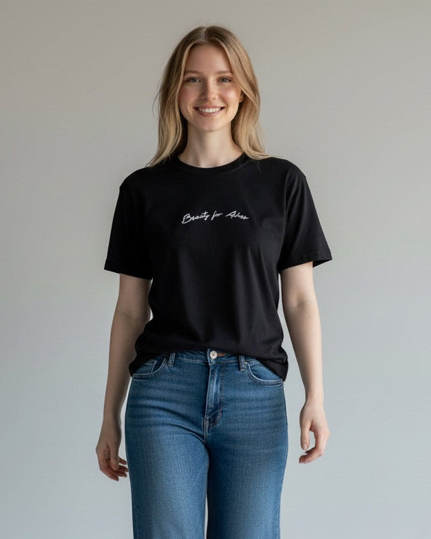 Woman wearing a black t-shirt and blue jeans against a plain background