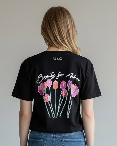 Person wearing a black t-shirt with floral design and text, standing against a plain background