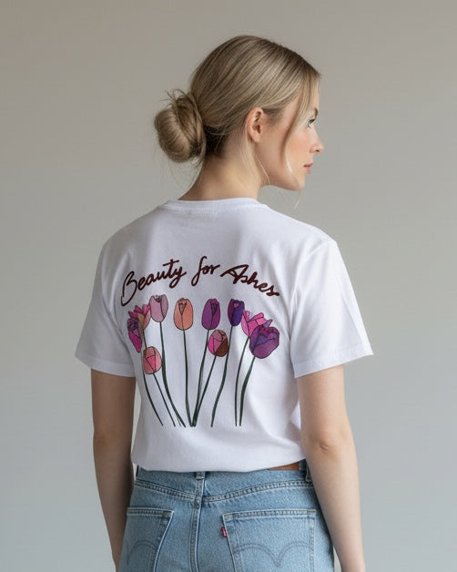 Woman wearing a white t-shirt with a graphic design and light blue jeans on a plain background