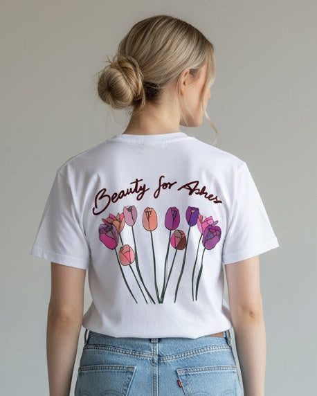 Person wearing a white t-shirt with floral design and text, paired with light blue jeans on a plain background