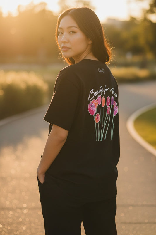 A gir wearing a black christian t-shirt with colorful floral design outdoors during sunset. Beauty for ashes