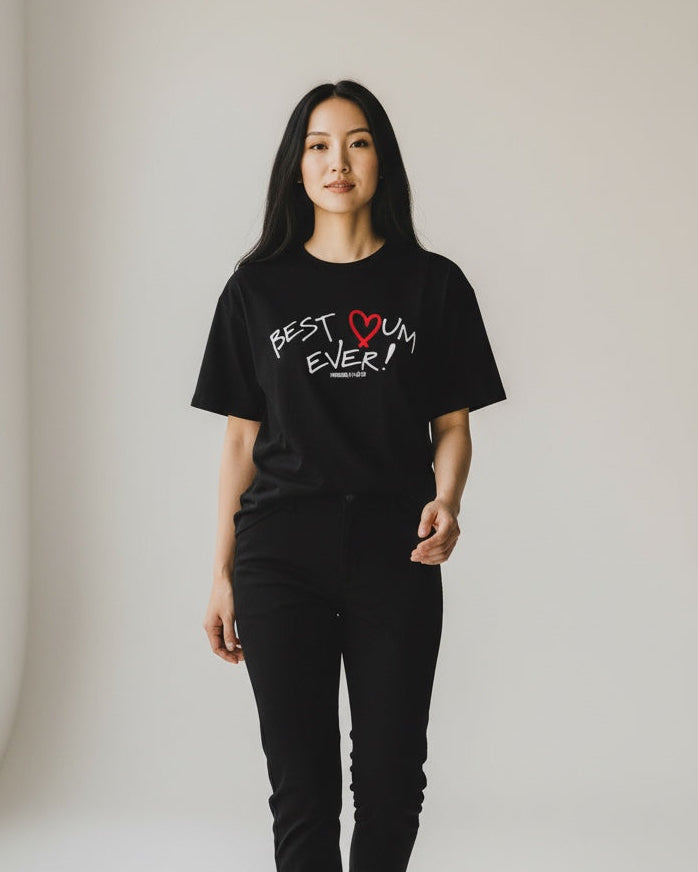 Person wearing a black t-shirt with text and design, standing in a minimalistic room.