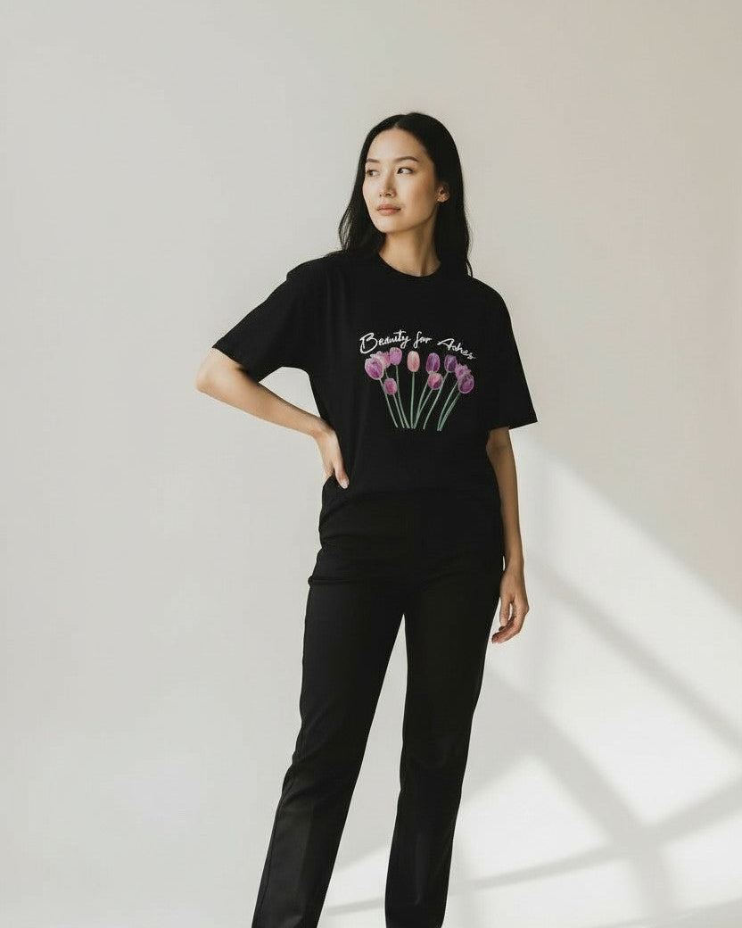 Person wearing a black christian t-shirt with a floral design and text, standing against a light background.