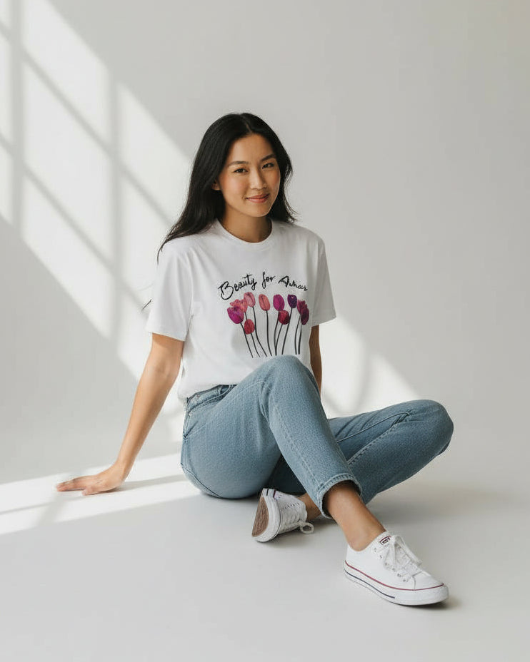 Woman wearing a christian white t-shirt with a graphic design, sitting on a light-colored floor.