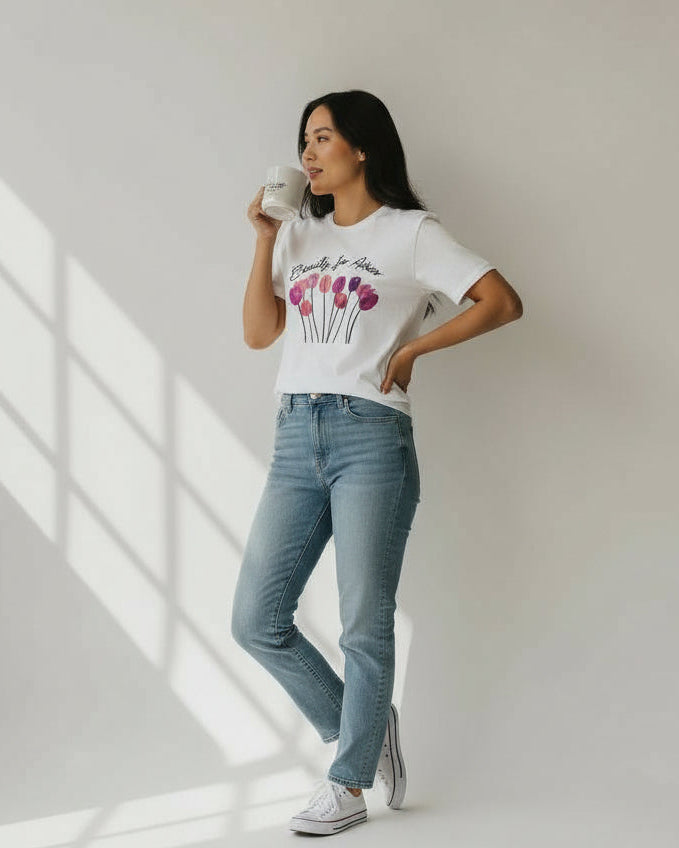 Woman wearing a christian white t-shirt with a graphic design and light blue jeans, standing in a well-lit room.