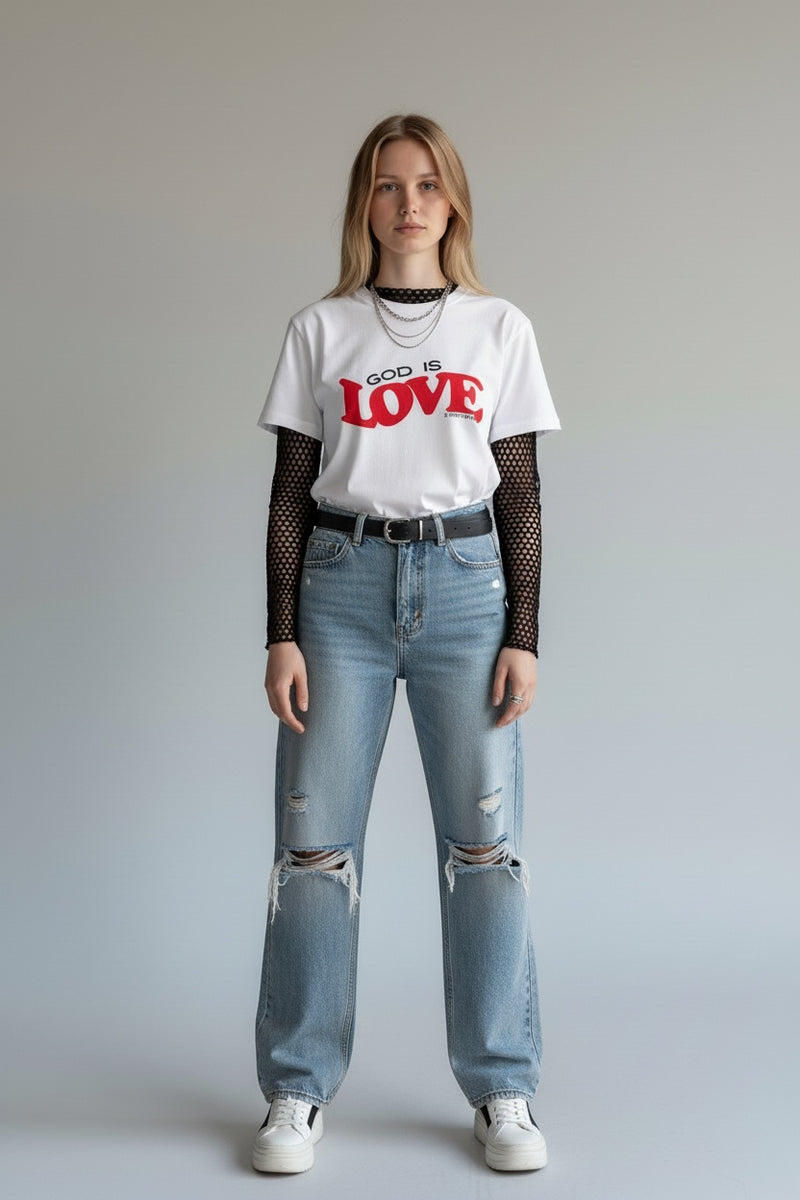Person wearing a white t-shirt with 'God is Love' text, blue jeans, and fishnet sleeves on a plain background