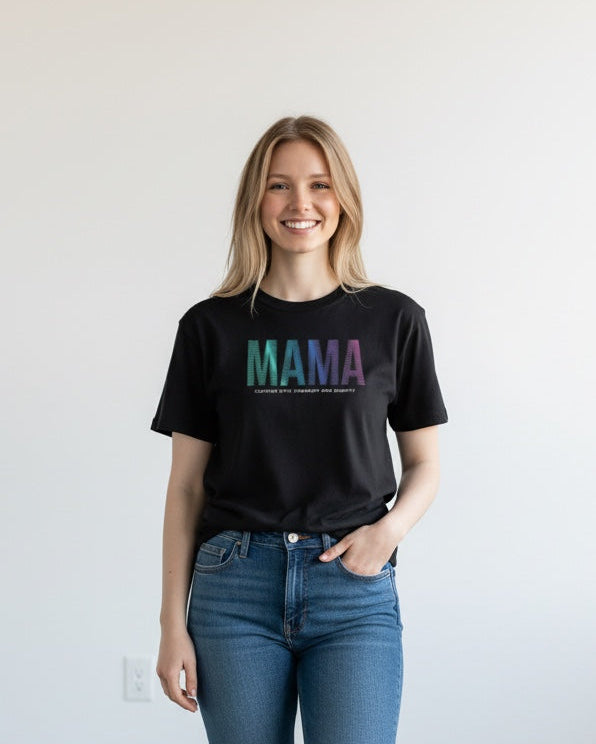 Woman wearing a black t-shirt with 'MAMA' printed in colorful letters, blue jeans, and white sneakers on a plain background.