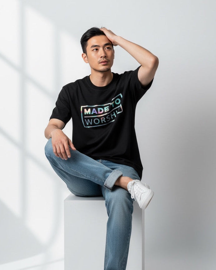 Man wearing a black t-shirt with text, sitting on a white surface with a light gray background