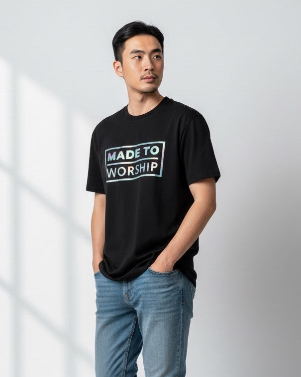 Man wearing a black t-shirt with 'Made to Worship' text, light blue jeans, and white sneakers on a white background.