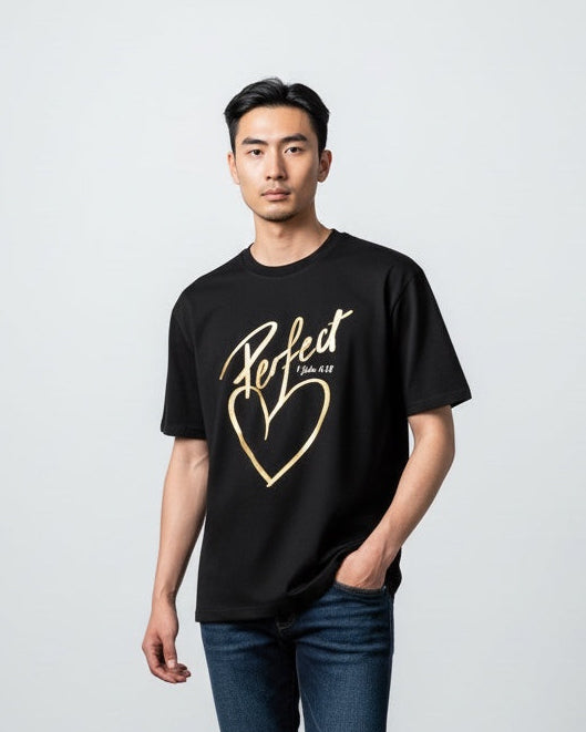 Person wearing a black t-shirt with a gold heart design on a plain background