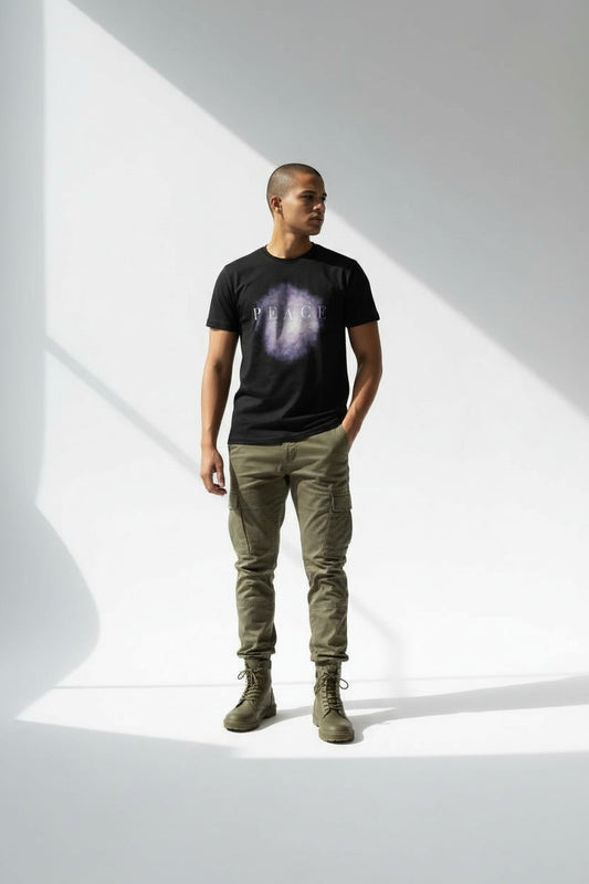 Man wearing a black t-shirt with a graphic design, green pants, and green boots on a white background