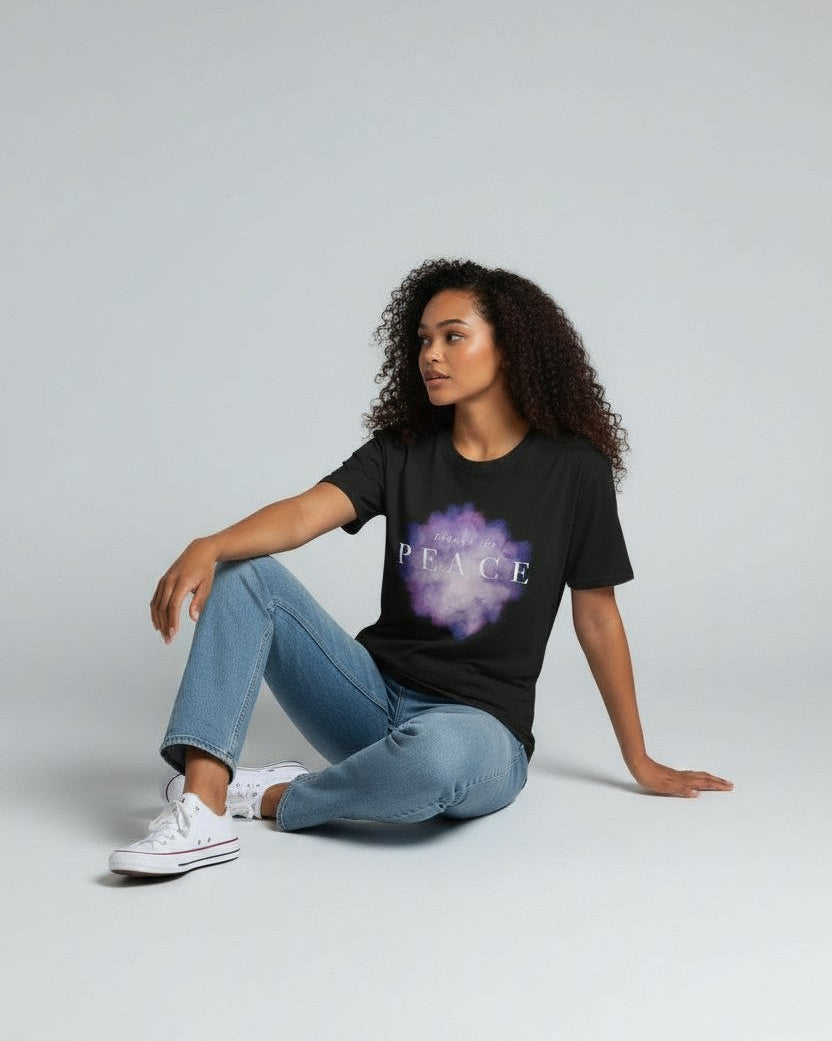 Person wearing a black t-shirt with a graphic design sitting on the floor against a plain background wearing a christian t-shirt that says prince of peace 