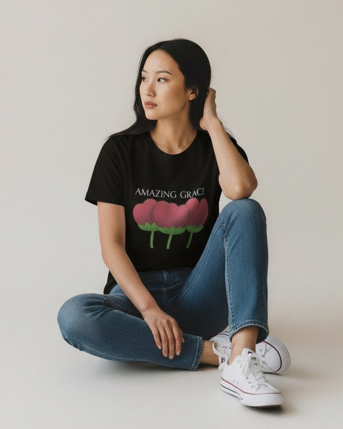 Woman wearing a black t-shirt with a graphic design sitting on a white floor.