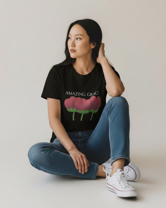 Woman wearing a black t-shirt with a graphic design sitting on a white floor.
