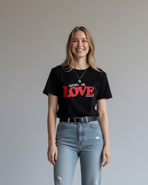 Person wearing a black t-shirt with 'God is Love' text and light blue jeans on a plain background