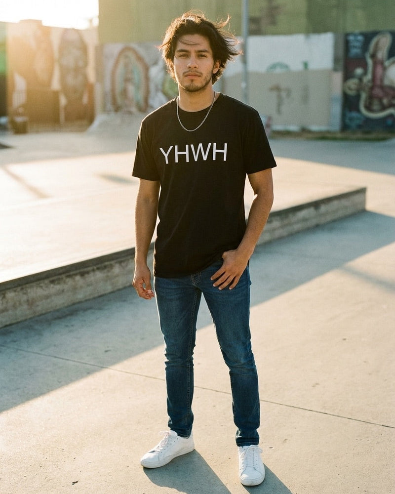 Man wearing a black t-shirt with 'YHWH' text at a skate park.