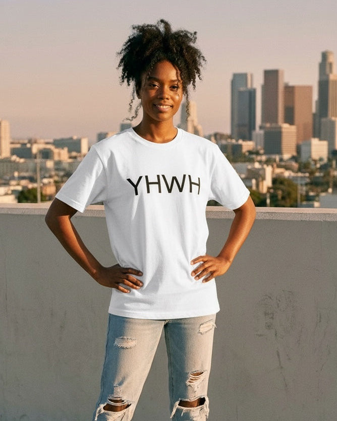 Person wearing a white t-shirt with 'YHWH' text, standing on a rooftop with city skyline in the background